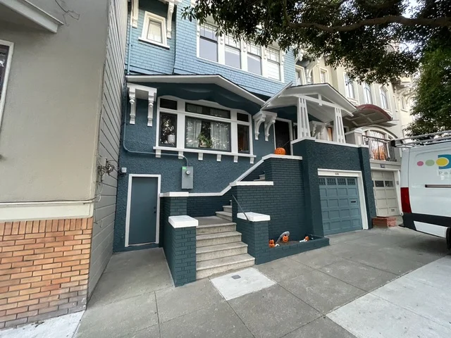 Blue-painted two-story house with white trim, garage, and concrete entry stairs