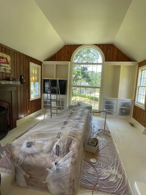Vaulted ceiling room with fresh paint, wood paneling, and arched window during painting project