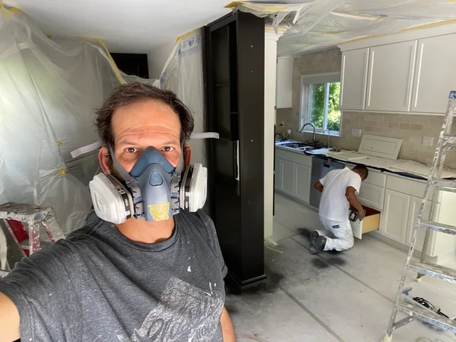 Painter wearing respirator mask during kitchen cabinet and wall painting project