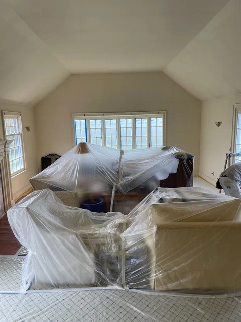 Bedroom interior with furniture covered in plastic sheeting for painting protection