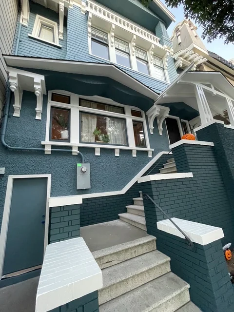 Two-story home with teal and light blue exterior paint, white trim, and painted concrete entry stairs