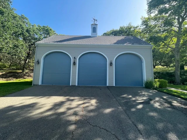White garage with three blue arched doors and fresh paint finish