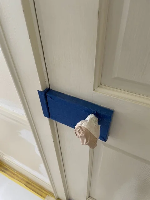 White interior door with blue painter's tape masking during painting project