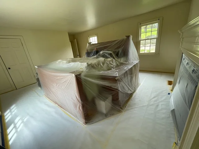 Bedroom interior with furniture covered in plastic sheeting for painting protection